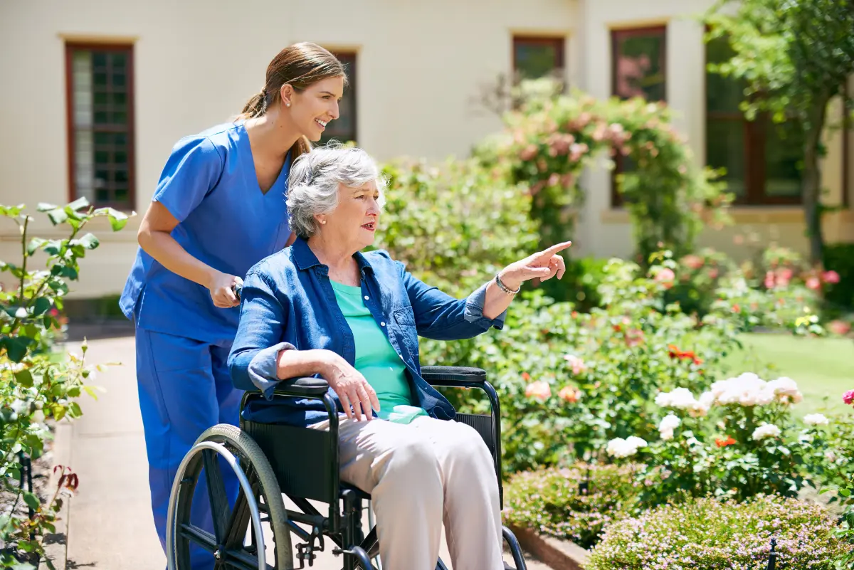 respite care resident in wheelchair outside aged care home being assisted by aged care nurse